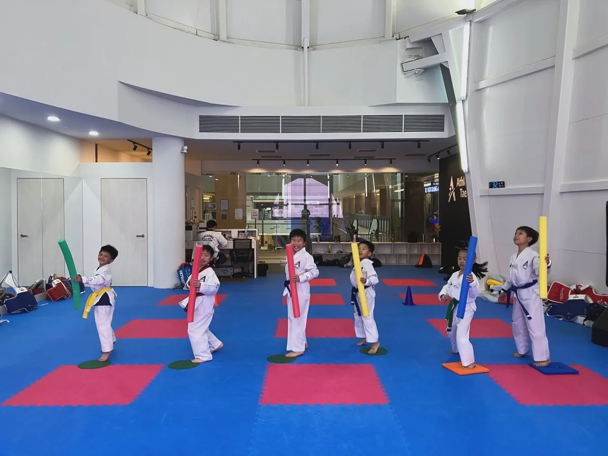 Kids taekwondo class in Singapore practising kicking drills with foam targets